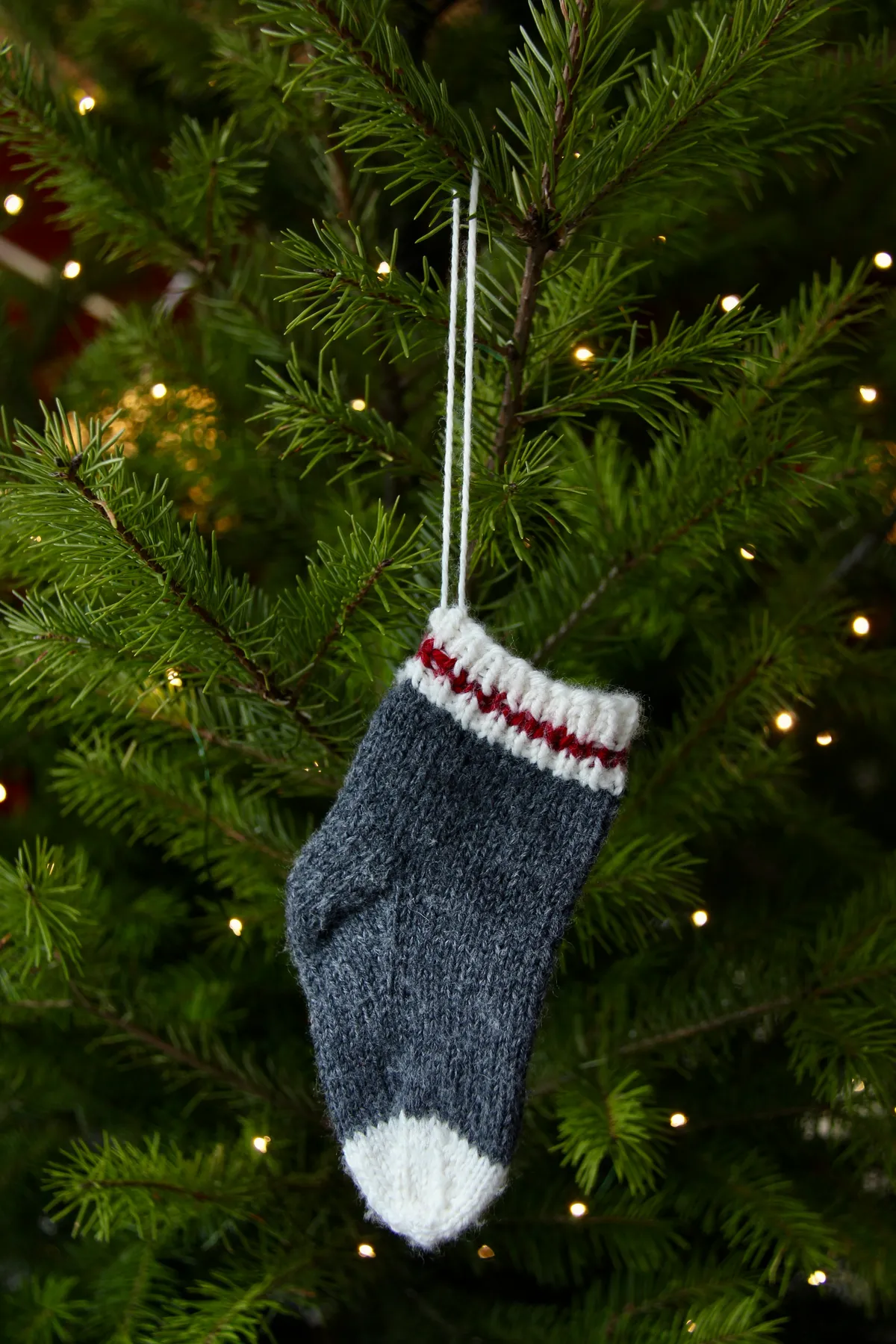 Sock Christmas tree ornament hanging on the tree with lights - knitted baby sock ornament
