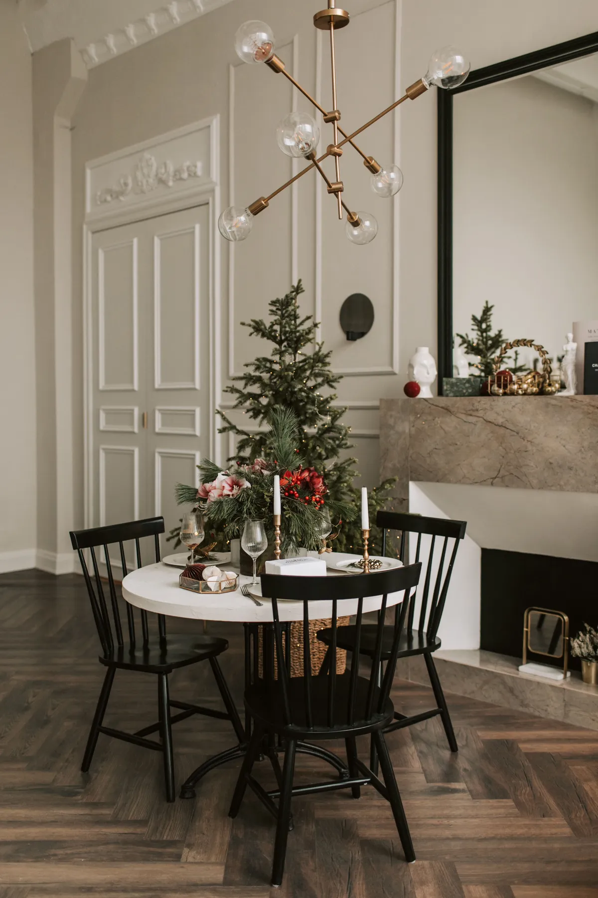 Stylish room with a Christmas tree, table, and modern chandelier, perfect for festive settings.