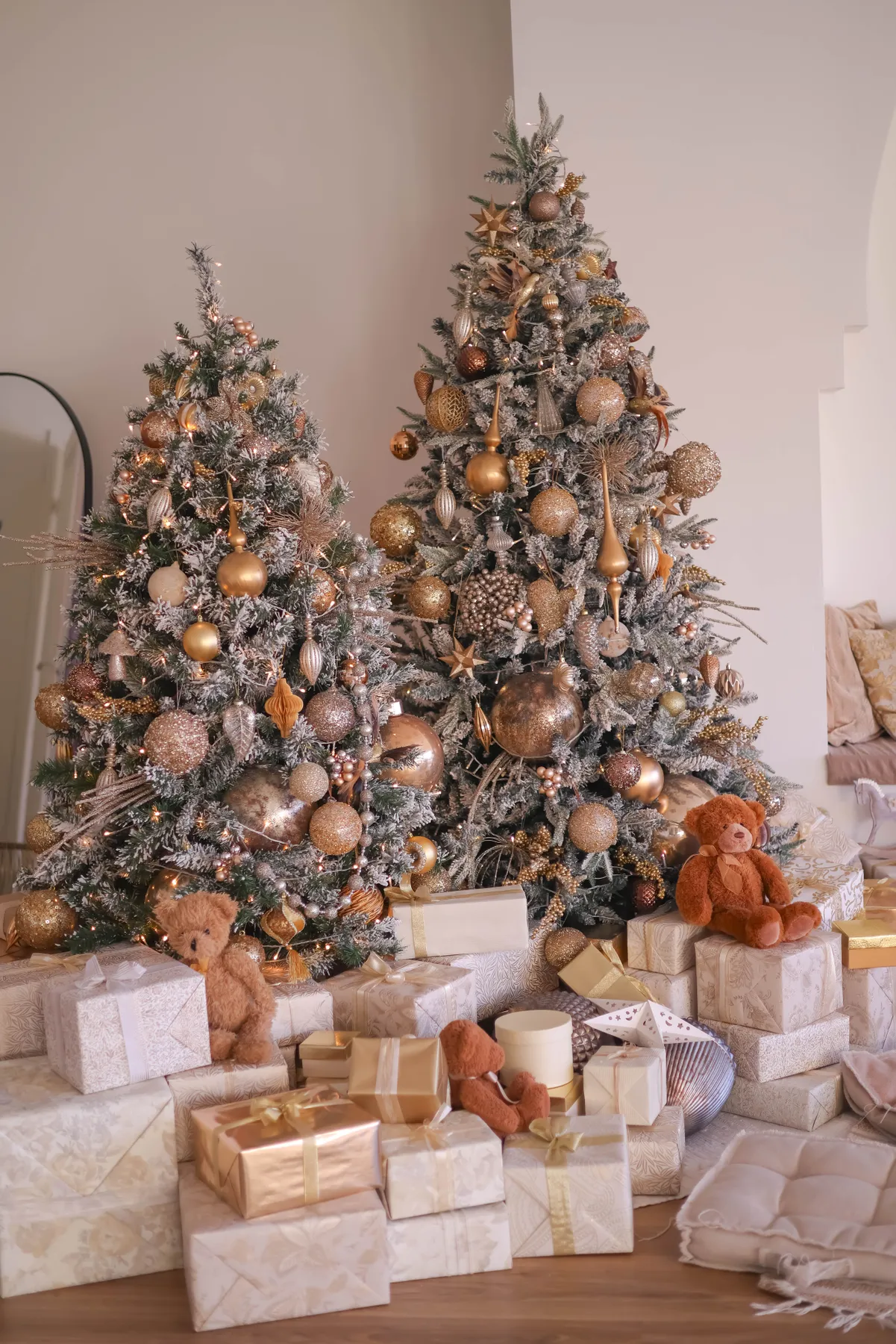 Two decorated Christmas trees with gifts and teddy bears in a cozy setting.