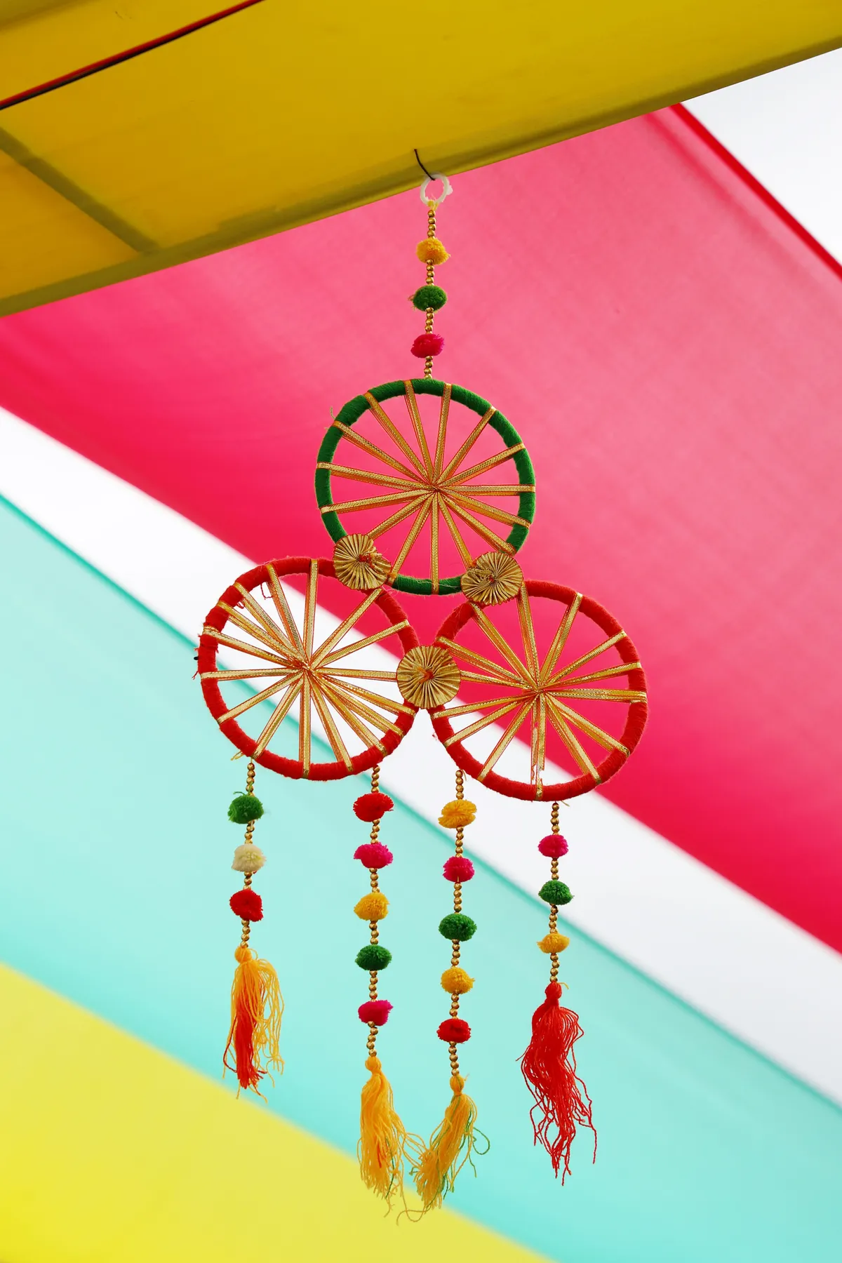Vibrant hanging decoration with colorful beads and tassels set against a bright background.
