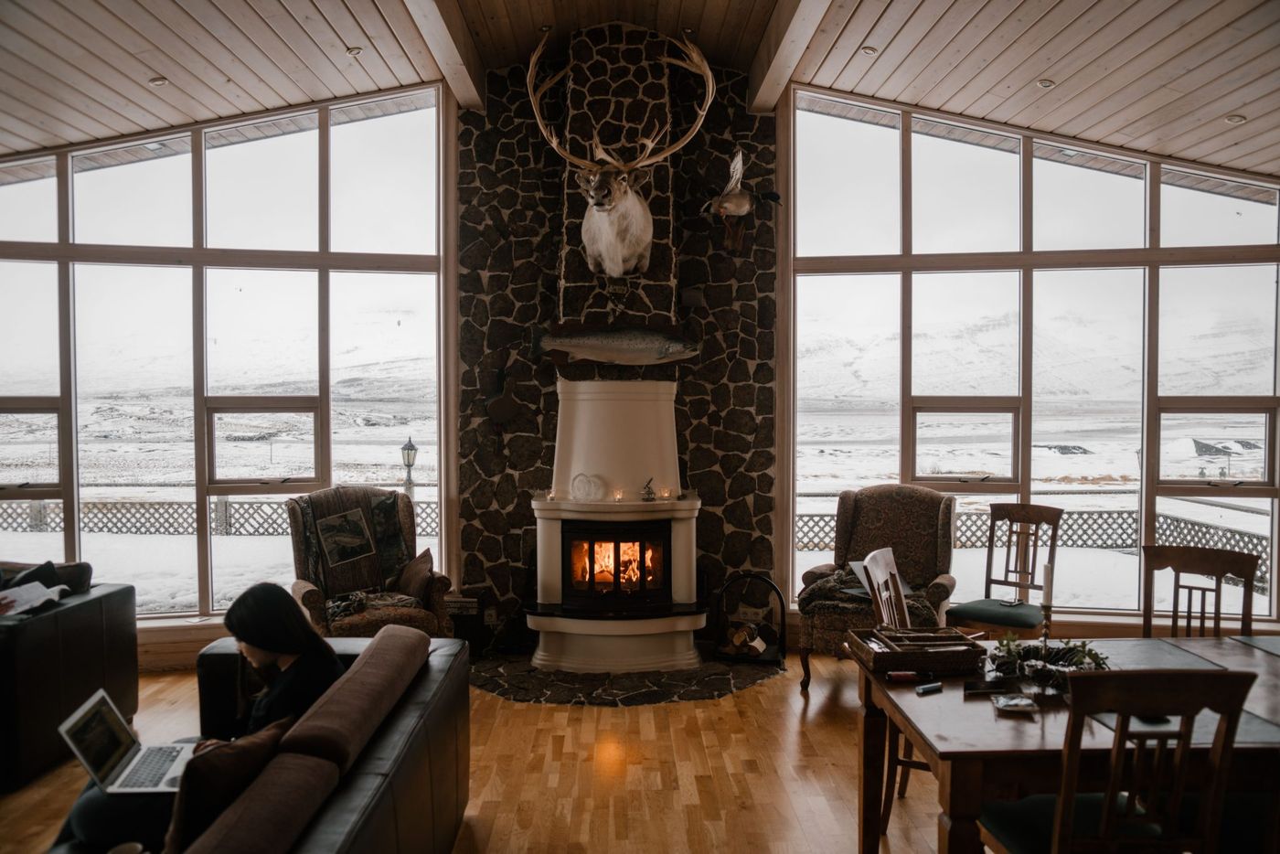Warm and inviting living room with a fireplace and large windows overlooking snow-covered mountains.