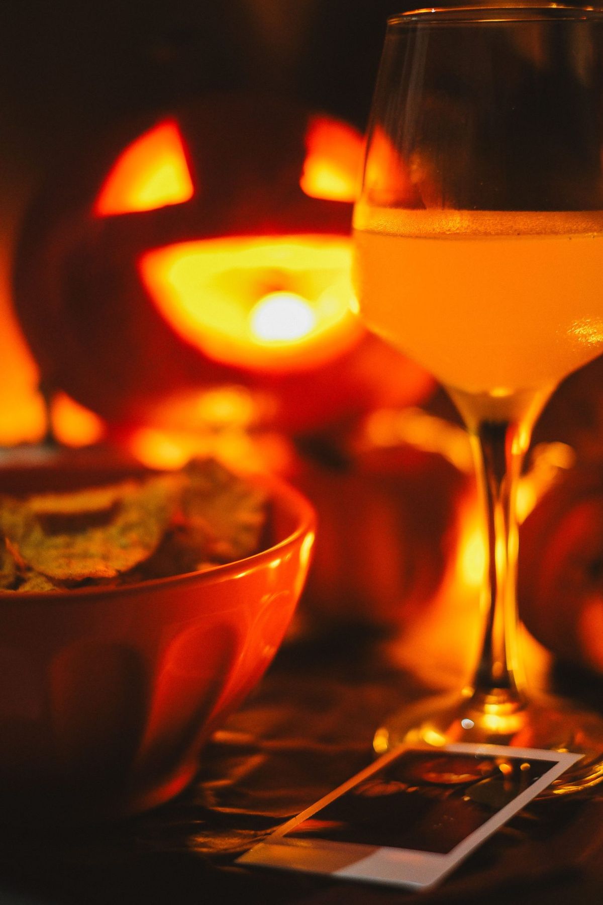 Warm autumn scene featuring a jack-o-lantern, cider glass, and chips, perfect for Halloween ambiance.