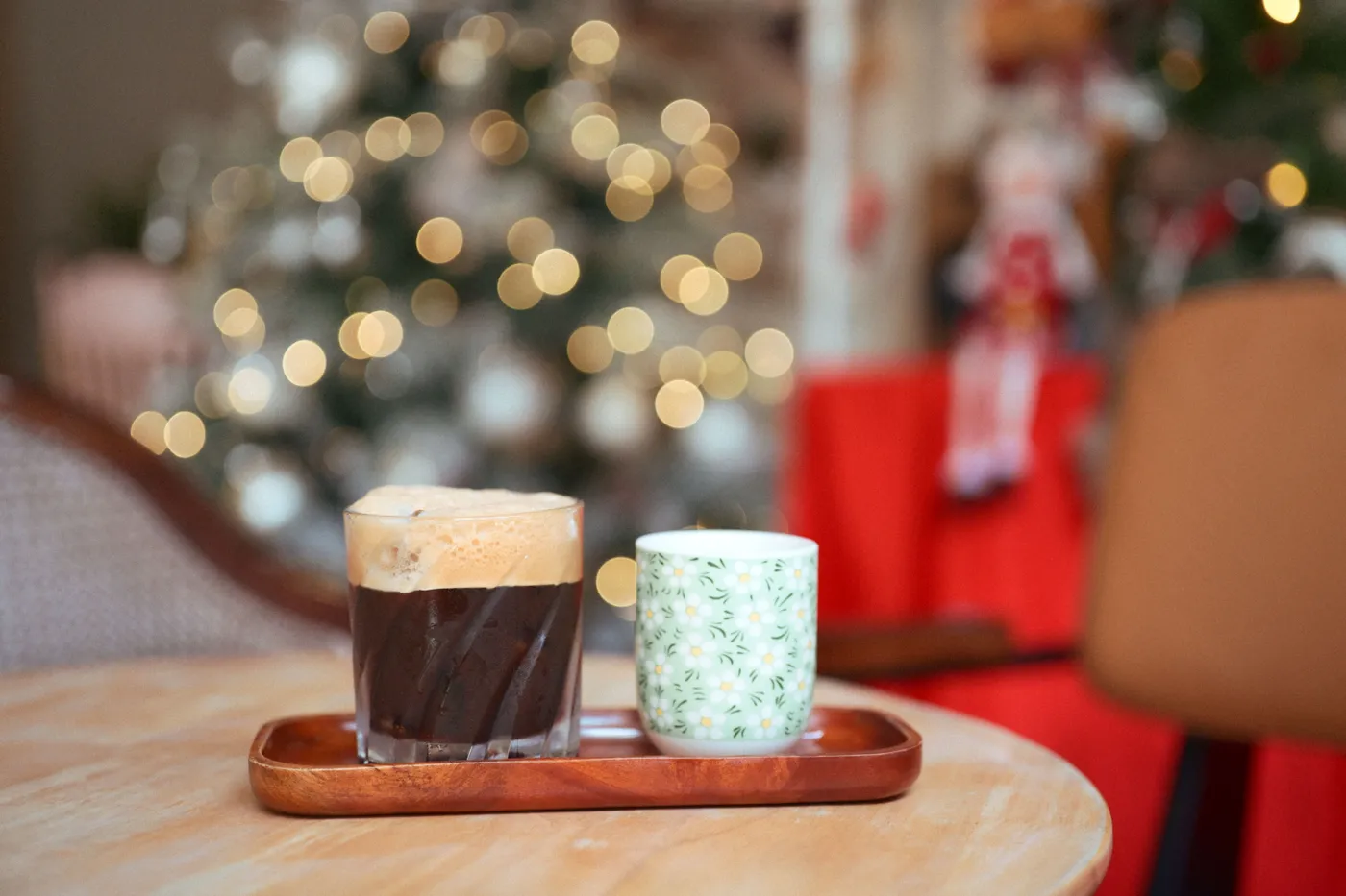 Warm coffee setting with holiday bokeh lights and festive decor indoors.