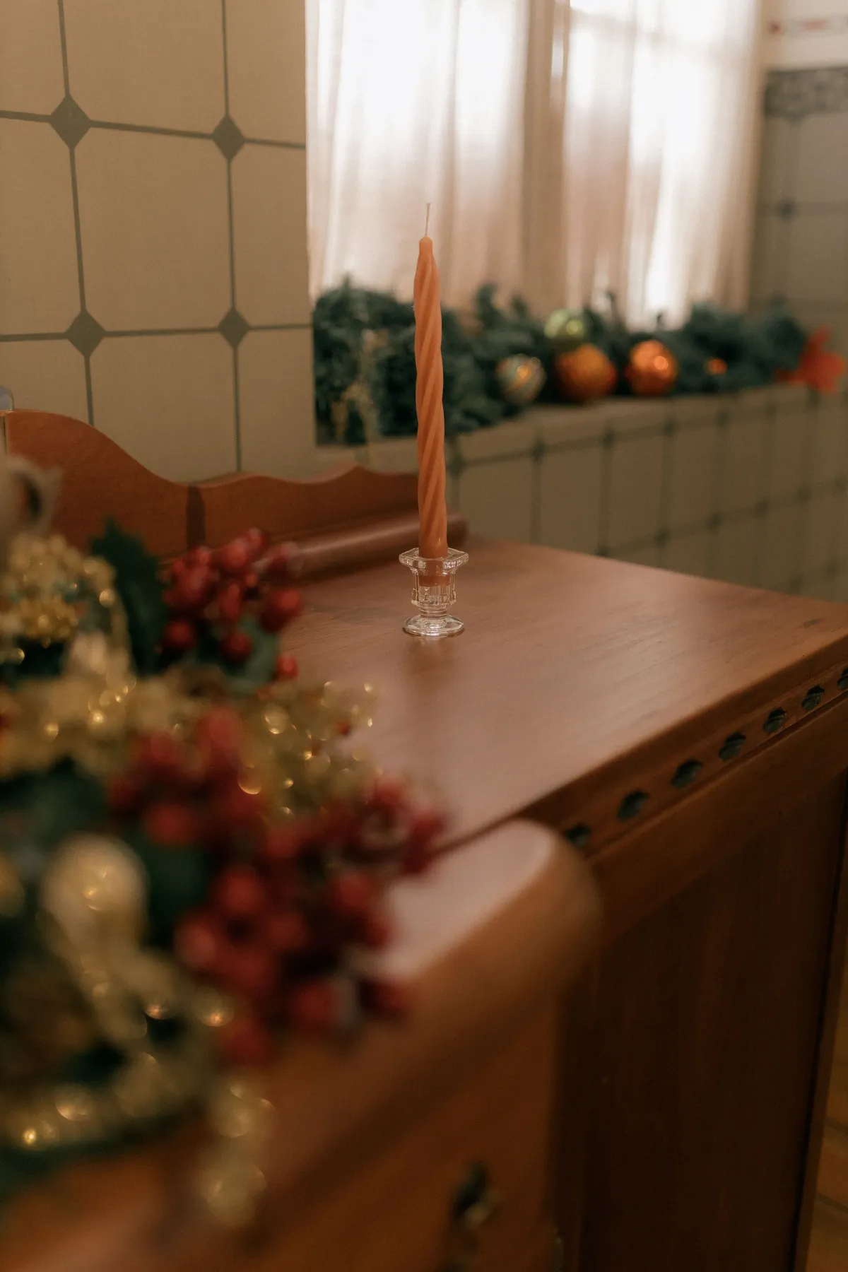 Warm, festive interior featuring a candle and Christmas ornaments on a wooden table.