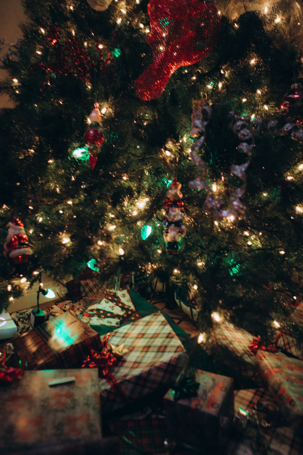 Warm holiday scene of a decorated Christmas tree with gifts underneath, featuring glowing lights.