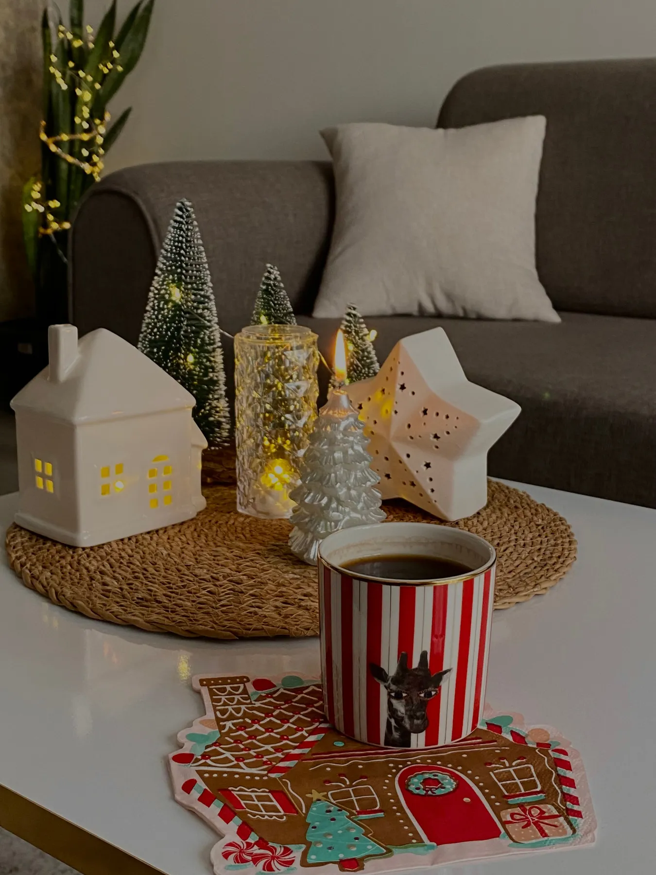 Warm indoor scene with holiday decor, a lit candle, and a festive mug.