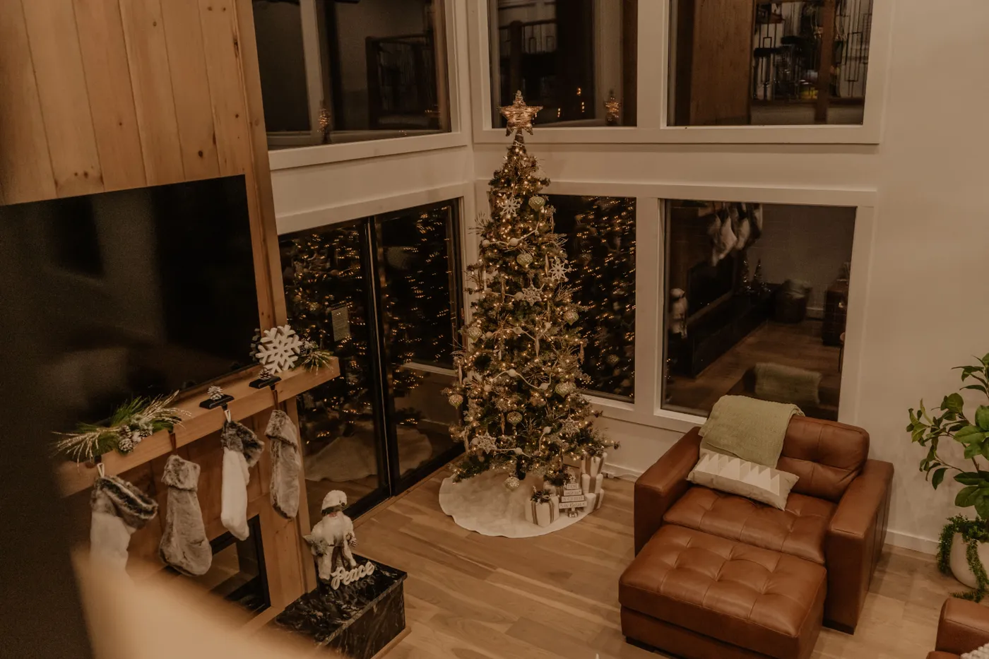 Warm living room scene with decorated Christmas tree and stockings by the fireplace.