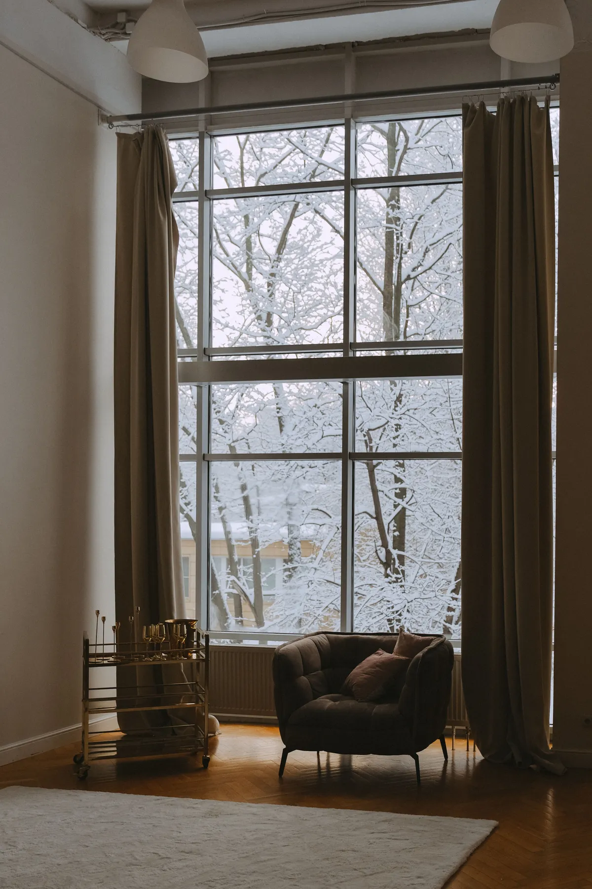 Warm room interior featuring an armchair and large windows with a snowy winter scene.