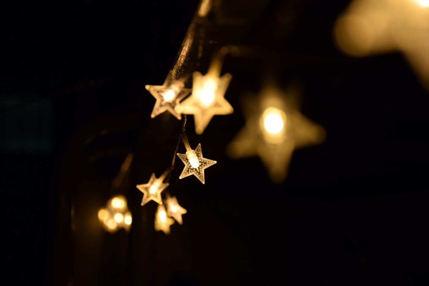 Warm star-shaped fairy lights hanging elegantly in the night, creating a festive ambiance.